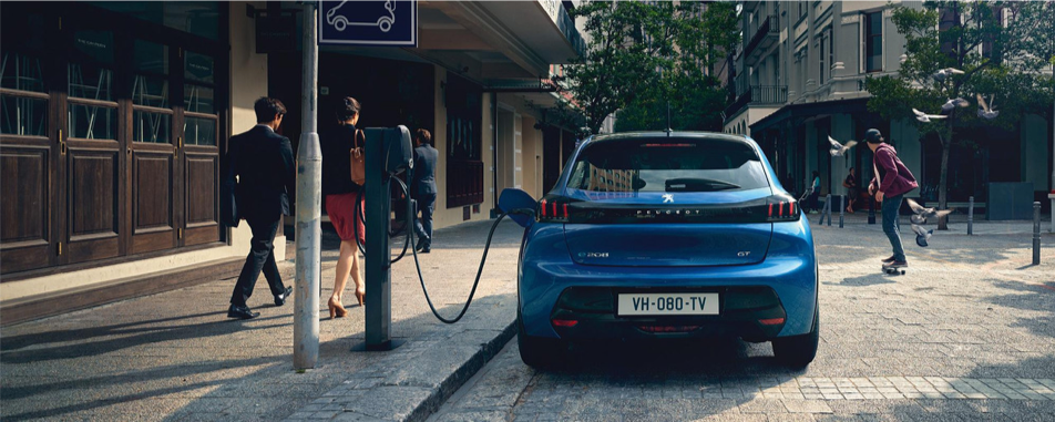 Peugeot e-208 bleue en charge sur une borne électrique en ville